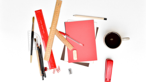 messy pile of overlapping office supplies flat layed on a white background